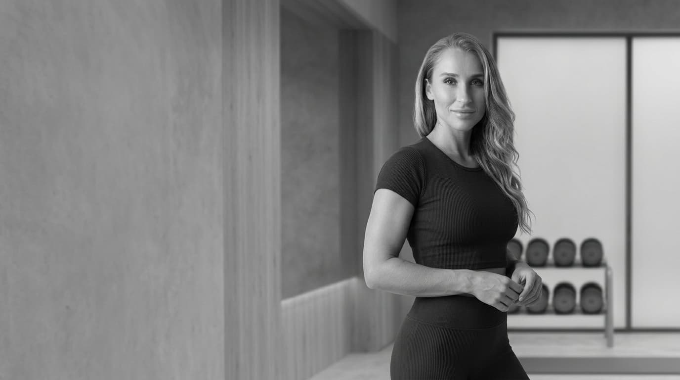 Summer standing in a refined private gym in a signature monochrome frame.