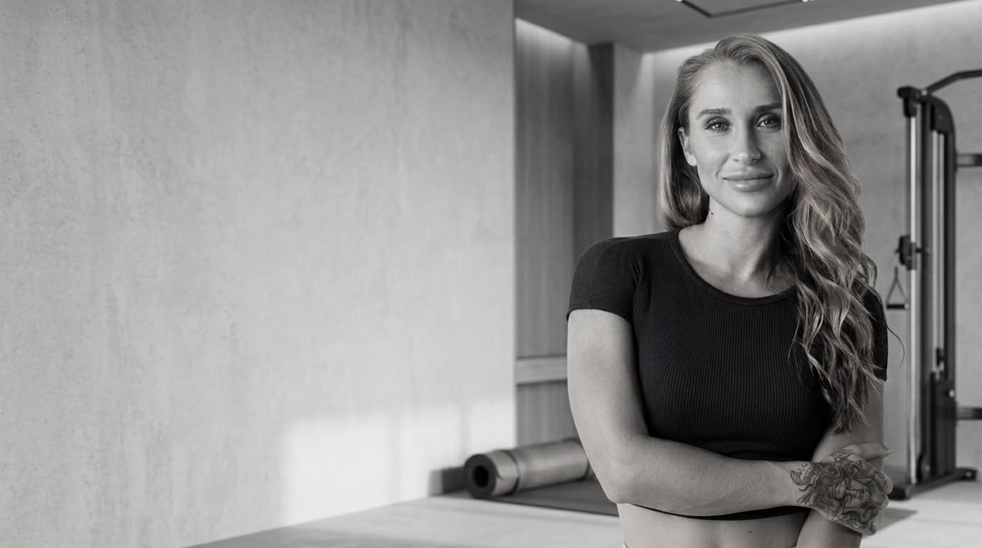 Black and white studio image of Summer standing in a refined private gym.